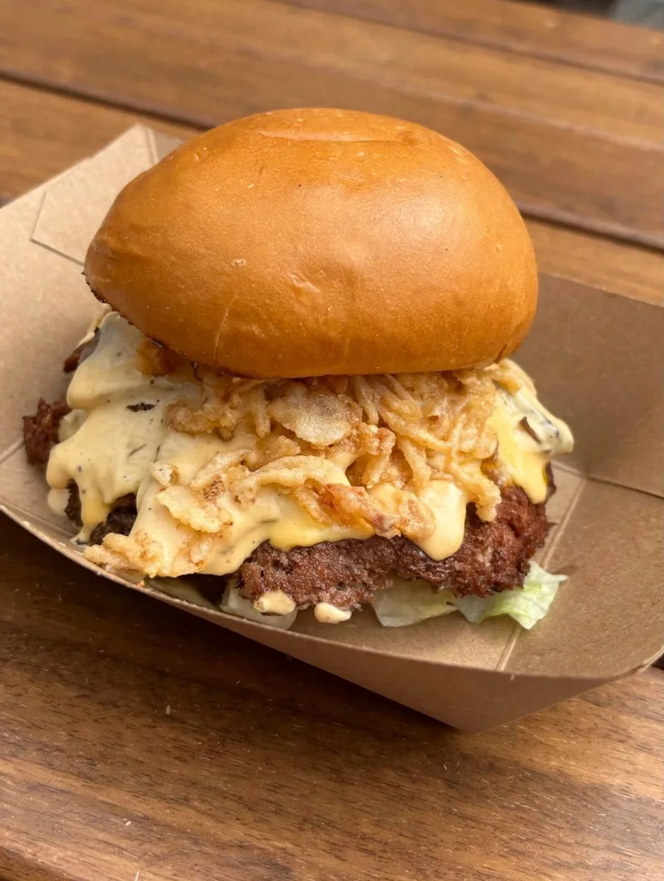 A smashed burger topped with crispy onions and creamy sauce